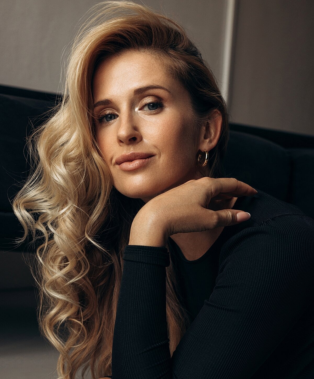 Model posing in neutral-colored lingerie against backdrop.