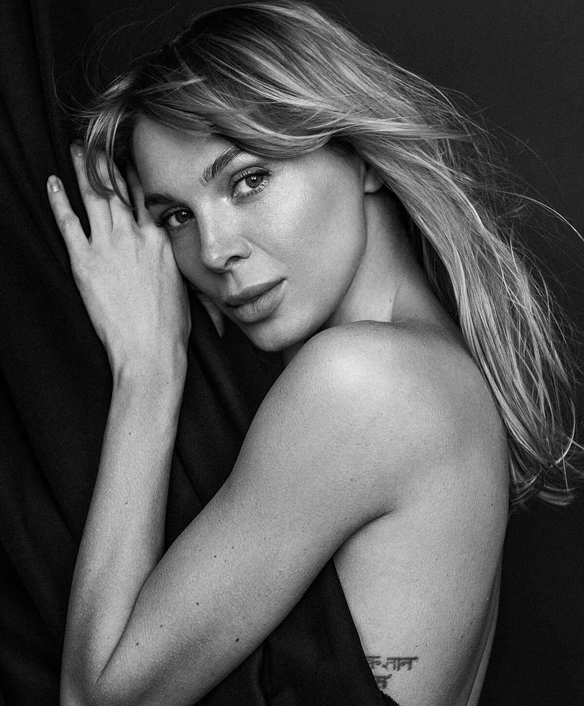 Model striking a pose against a textured wall.