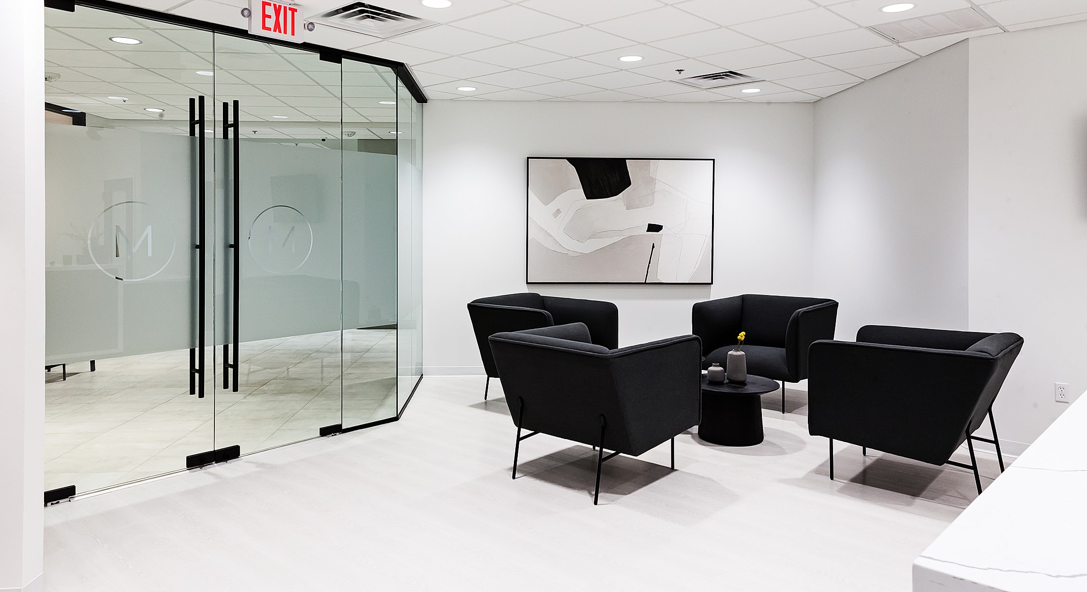 Modern office waiting area with black chairs.
