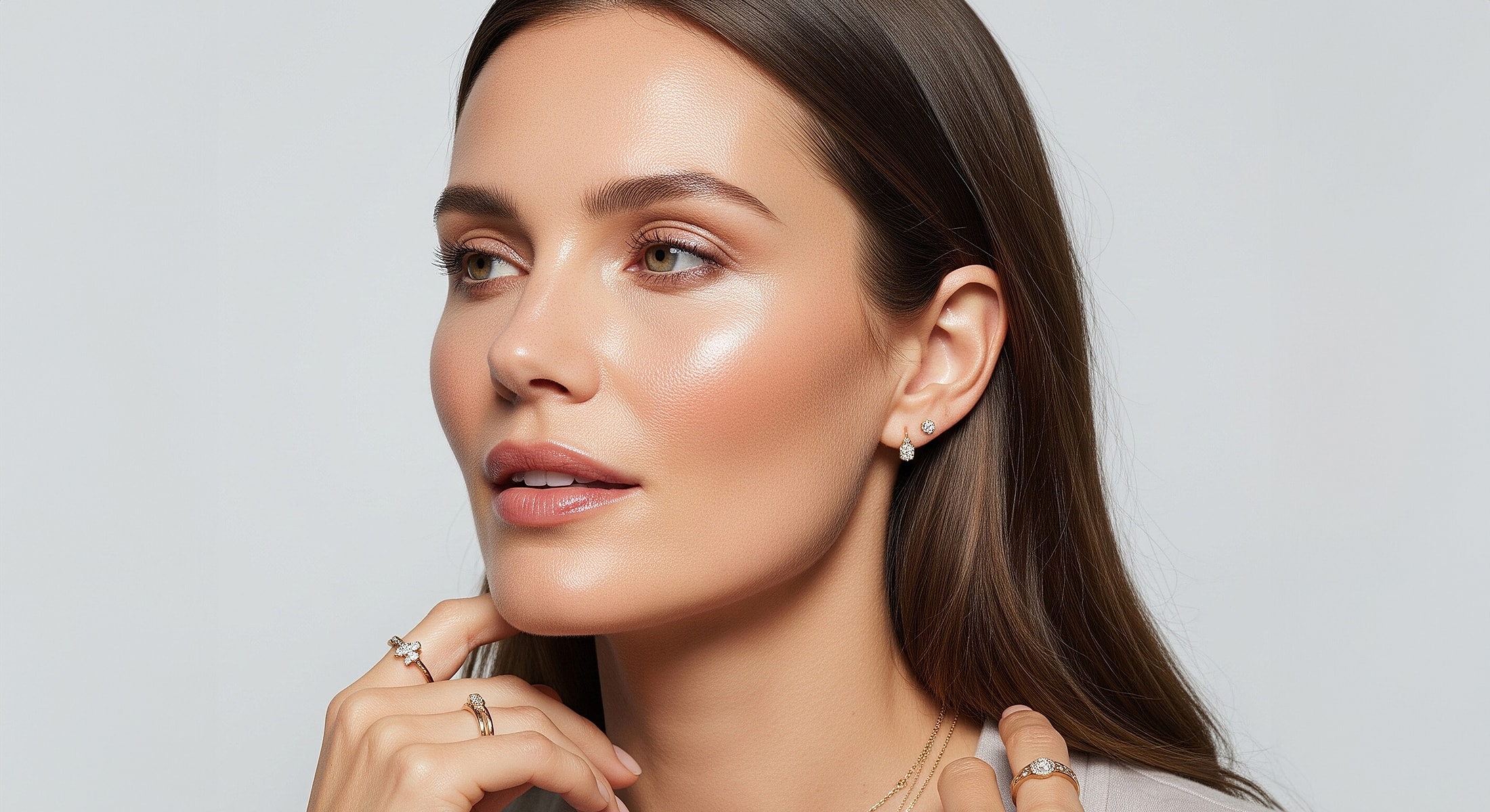 Woman showcasing jewelry and glowing makeup.