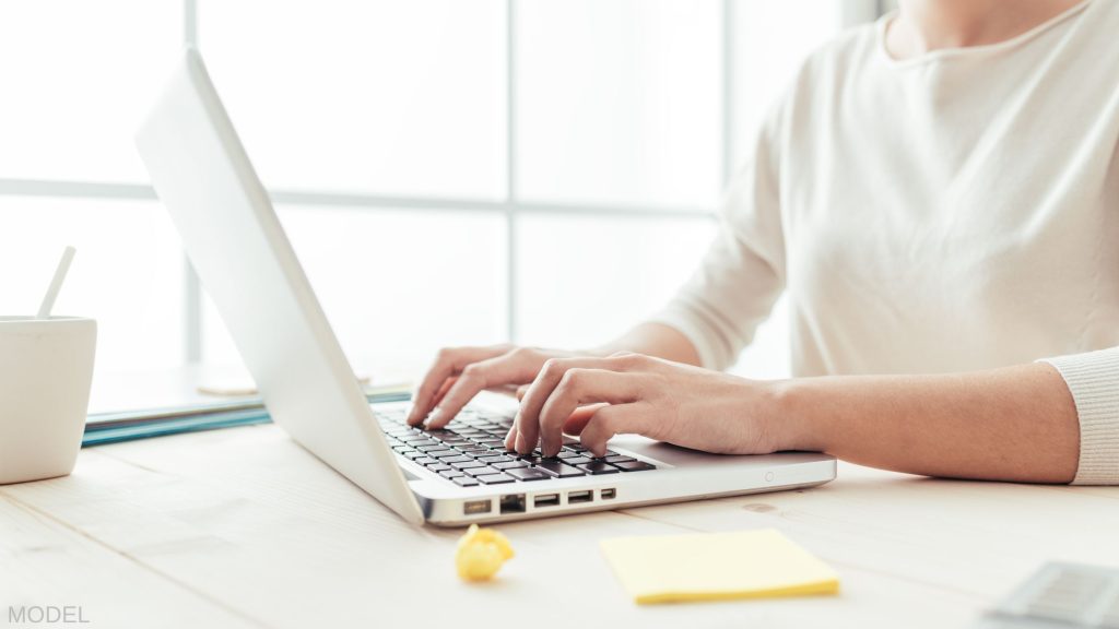 Woman with hands on keyboard of a laptop (MODEL)