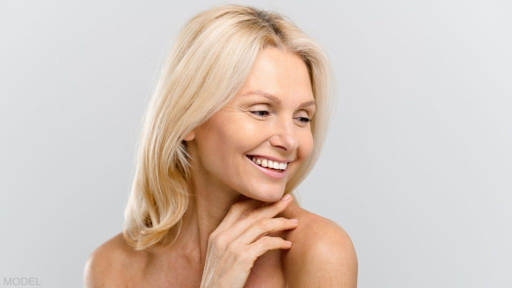 Mature woman looking over her shoulder with her hand under her chin. (MODEL)